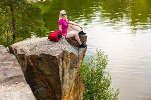 Hiker with backpack relaxing on a rock and enjoying sunset photo