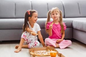 Portrait of cute little girl sitting and eating pizza photo