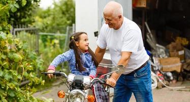 feliz abuelo y su nieta cerca de la bicicleta sonriendo foto