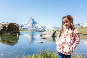 Cute little girl outdoors in the lawn and admiring mountains view in mountain in switzerland photo