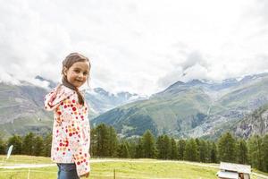 Children hiking in Alps mountains. Kids look at snow covered mountain. Spring family vacation. Little girl on hike trail in alpine meadow. Outdoor fun and healthy activity. photo
