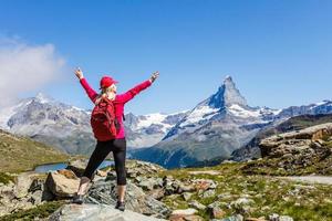 Hiking in the swiss alps with flower field and the Matterhorn peak in the background. photo