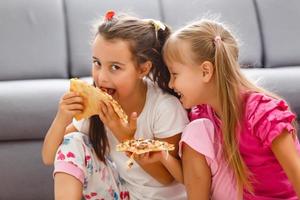 retrato de una linda niña sentada y comiendo pizza foto