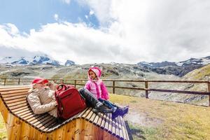 mother and daughter with backpack sitting on the footpath in the mountains at the day time. photo