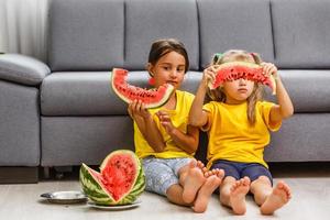 Child eating watermelon, two little girls eat watermelon at home photo