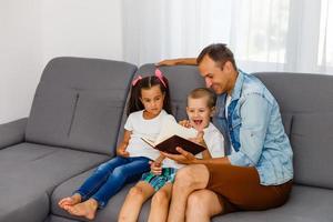 Young father reading book to little children photo