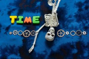 Time wording beside  cogwheels and  artificial skeleton as time concept photo