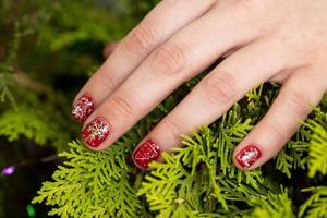 un primer plano del diseño de manicura de uñas rojas con copos de nieve en el árbol de navidad foto
