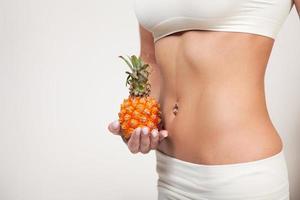 Beautiful female belly and pineapple on white background photo
