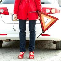 mujer sostiene un signo de triángulo rojo y una llave inglesa y espera asistencia en la carretera foto