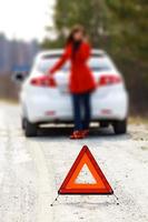 Woman standing by the broken car and warning triangle sign photo