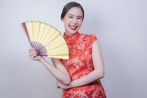 Asian woman in national dress of Chinese new year holding yellow wood fan in soft isolated background