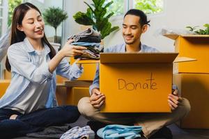 Close up box of donation, man holding clothes packing and woman fold clothes and prepare to give poor people photo