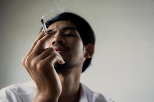 World No Tobacco Day in May, stop smoking and against  concept, young man holding cigarette in dark tone photo