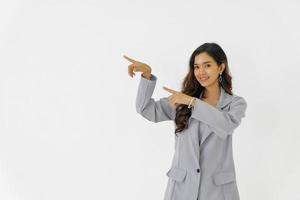 feliz joven asiática hermosa mujer de negocios de pie señalando con el dedo para copiar espacio sobre fondo blanco aislado. foto