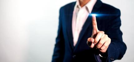 Businessman pressing button on blue light virtual screen. Man pointing on futuristic interface. Innovation technology internet and business concept. Space for text and words. Abstract background. photo