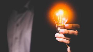 Man hand holding a light bulb. Ideas, innovations and inspiration. Creative idea with sparkling light bulbs. concept of crisis photo