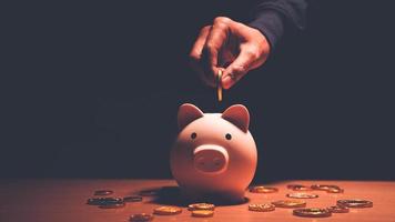 ahorrar dinero, la planificación financiera de las finanzas personales y ser un concepto ahorrativo con una alcancía rosa sentada en una mesa de madera. foto