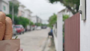 The delivery man wears red shirts and masks holding food bag paper. The staff stand at the front door of the customers ordering products online. Food delivery man put ring the bell for sent goods. video