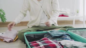 una mujer dobla su ropa y la pone en su bolso para prepararse para un viaje. una mujer prepara sus maletas para su viaje de trabajo. el concepto de preparación para viajar. video