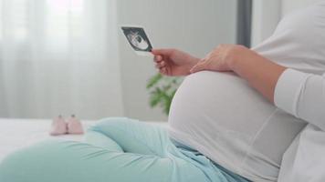 gravid kvinna var tittar på de ultraljud av henne dotter i henne livmoder. ultraljud bilder kan hjälp visa de bebis handla om utveckling. begrepp av foster- vård. video