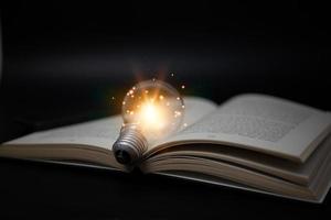 Bright lamp or glowing light bulb with book or textbook. Business success idea or solution concept. Thinking power of business person or professional. Working, studying or learning inspiration photo