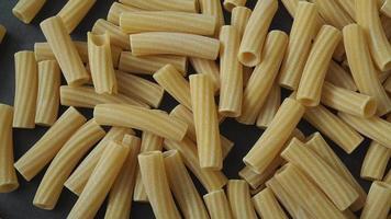 Raw italian penne rigate pasta isolated on black background video