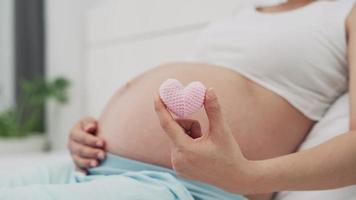 zwanger vrouw beweging hart roze en tonen liefde naar de ongeboren kind. de roze hart vertegenwoordigt een vrouw gevoelens voor de belang van de kind. moeder-kind verhouding concept. video