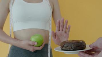 dieta y dieta. belleza cuerpo femenino delgado confundir donut. mujer con ropa de ejercicio logra el objetivo de pérdida de peso para una vida saludable, loca por la delgadez, cintura delgada, nutricionista. video