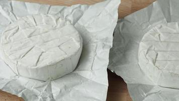 cabeça de queijo dois camembert em papel branco na tábua. preparação para grelhar video