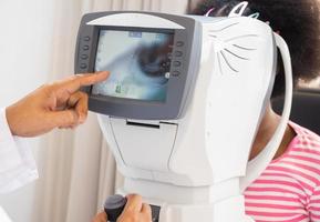 The ophthalmologist is checking the eye vision of the attractive young girl in a modern clinic. diagnostic ophthalmology equipment photo