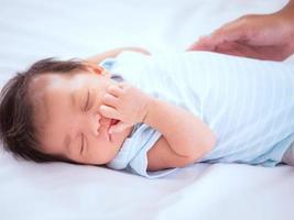 retrato de un bebé o bebé recién nacido asiático australiano de tres semanas acostado en la cama blanca y cierra los ojos. foto