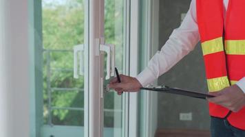 inspecteur ingenieur is inspectie apparaat van de deur na installatie. aannemer is test de slot van de glas deur voordat levering naar de klant. huis inspectie concept door een ingenieur. video