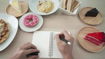 concepto de evitar la grasa para la dieta. la mujer está perdiendo peso y escribe la palabra grasa en su cuaderno para recordarle la pérdida de peso. los alimentos grasos o los bocadillos causan obesidad. video