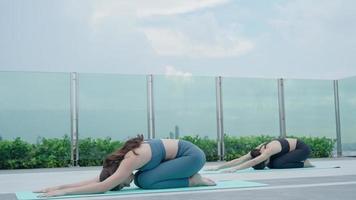 mujer delgada practicando yoga en el balcón de su condominio. mujer asiática haciendo ejercicios por la mañana. equilibrio, meditación, relajación, calma, buena salud, feliz, relax, concepto de estilo de vida saludable video