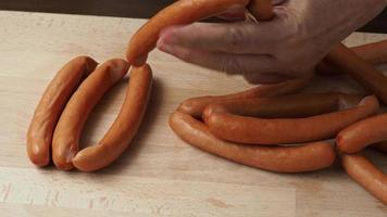 Thin pork sausages on the wooden cutting board video