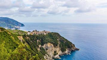 Fishing boats moored on water in harbor of Ligurian and Mediterranean Sea near coastline of Riviera di Levante of National park Cinque Terre Coast with blue sky, Riomaggiore village, Liguria, Italy. photo