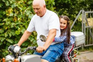 feliz abuelo y su nieta cerca de la bicicleta sonriendo foto