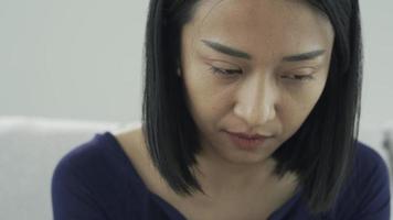 Close up face sad thoughtful young asian single woman looking away thinking of problems sit alone at home troubled negative. depressed and tension on life concept. video