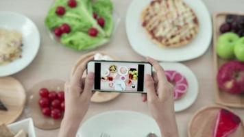 net idol e tirar foto para revisão de comida. as mulheres usam telefones celulares para tirar fotos de comida ou gravar vídeos ao vivo em aplicativos de redes sociais. comida para o almoço parece apetitosa. video