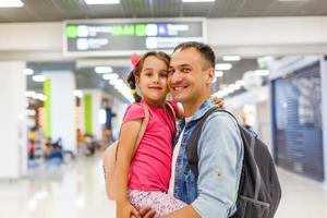 papá está abrazando a la niña en el pasillo del aeropuerto con felicidad. foto