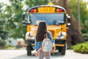 niña con mochila va al autobús escolar foto