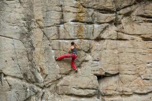 A young woman with a rope engaged in the sports of rock climbing on the rock. photo