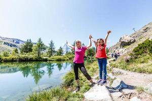 Happy hiker woman and girl at mountains lake photo