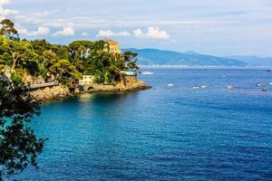 Fishing boats moored on water in harbor of Ligurian and Mediterranean Sea near coastline of Riviera di Levante of National park Cinque Terre Coast with blue sky, Riomaggiore village, Liguria, Italy. photo