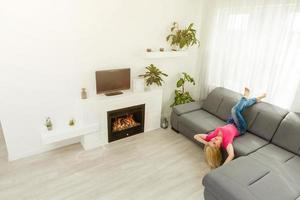 retrato de una chica relajándose en un sofá después del trabajo en casa sentada en un sofá en la sala de estar en casa con una cálida luz de puesta de sol foto