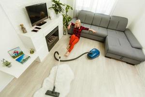mujer limpiando la aspiradora de suelo en el moderno salón blanco foto