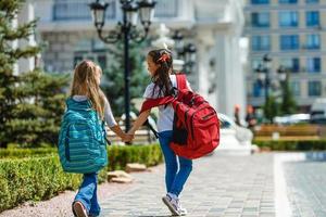 two little schoolgirls with heavy backpacks go to school photo