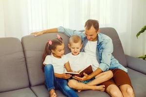 Young father reading book to little children photo