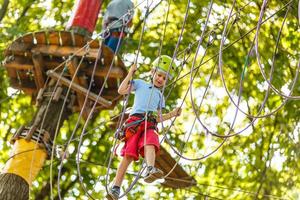 niños pequeños felices en un parque de cuerdas en el fondo de madera foto